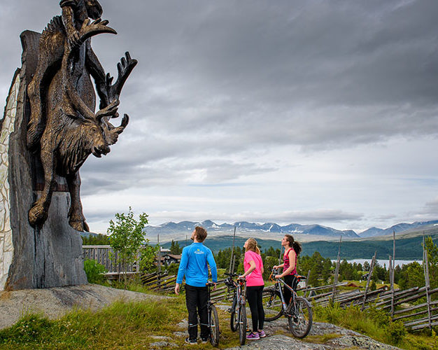 Møte mellom skulptur og syklister på Kvamsfjellet, med Rondane i bakgrunnen.